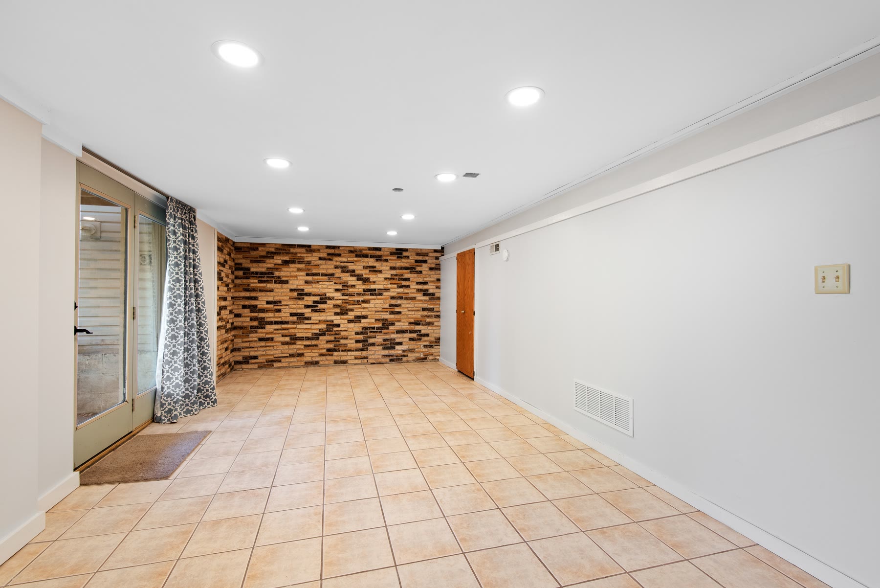 Finished basement living space with seating, shelving, flooring, and a fireplace